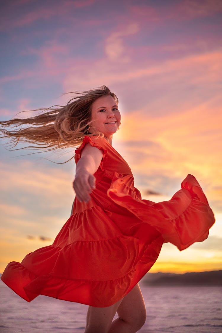 Smiling Woman In Flying Red Dress At Sunset