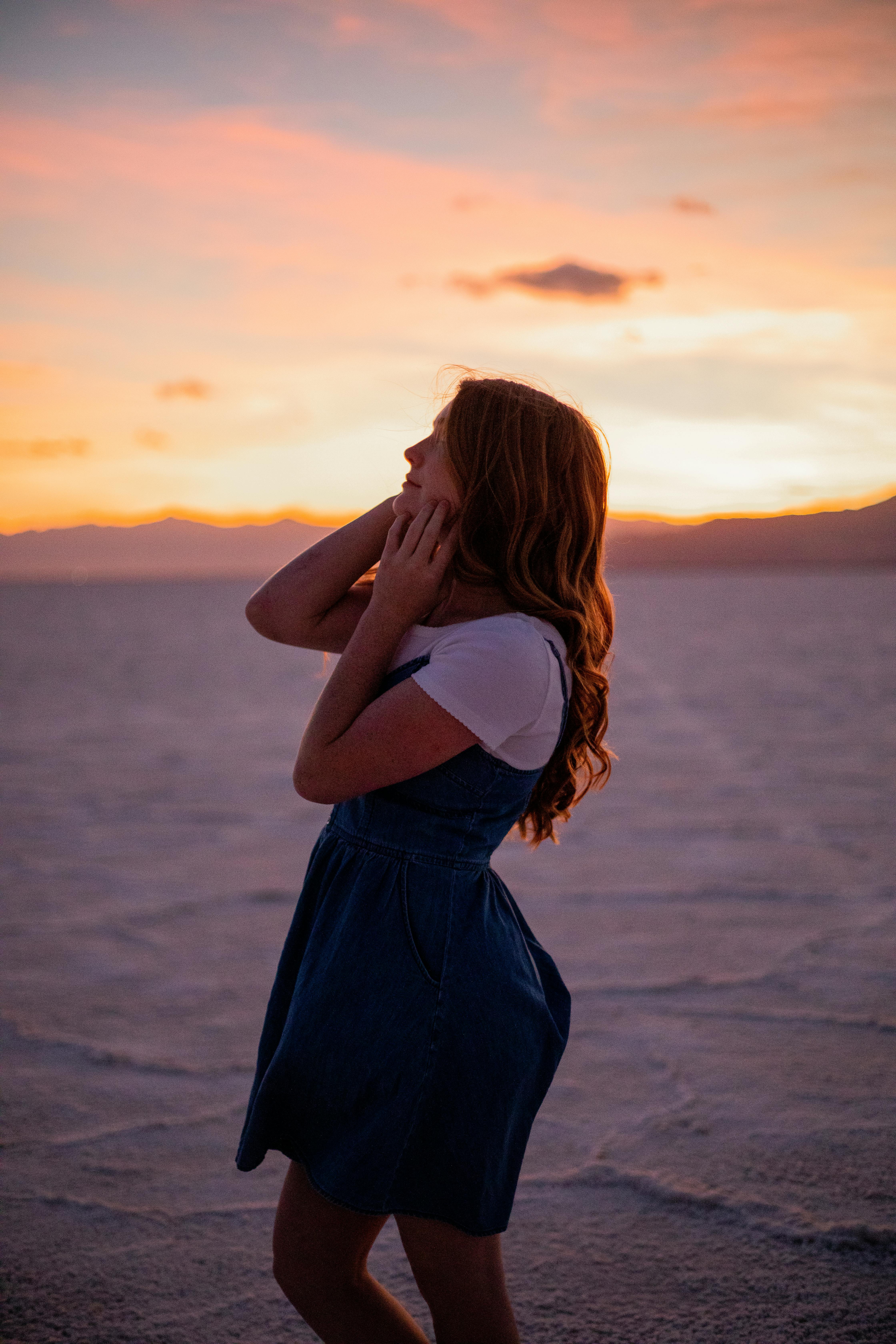 在开阔的风景中，卷发的女人正享受着宁静的日落，心中涌起一片安宁与温暖
