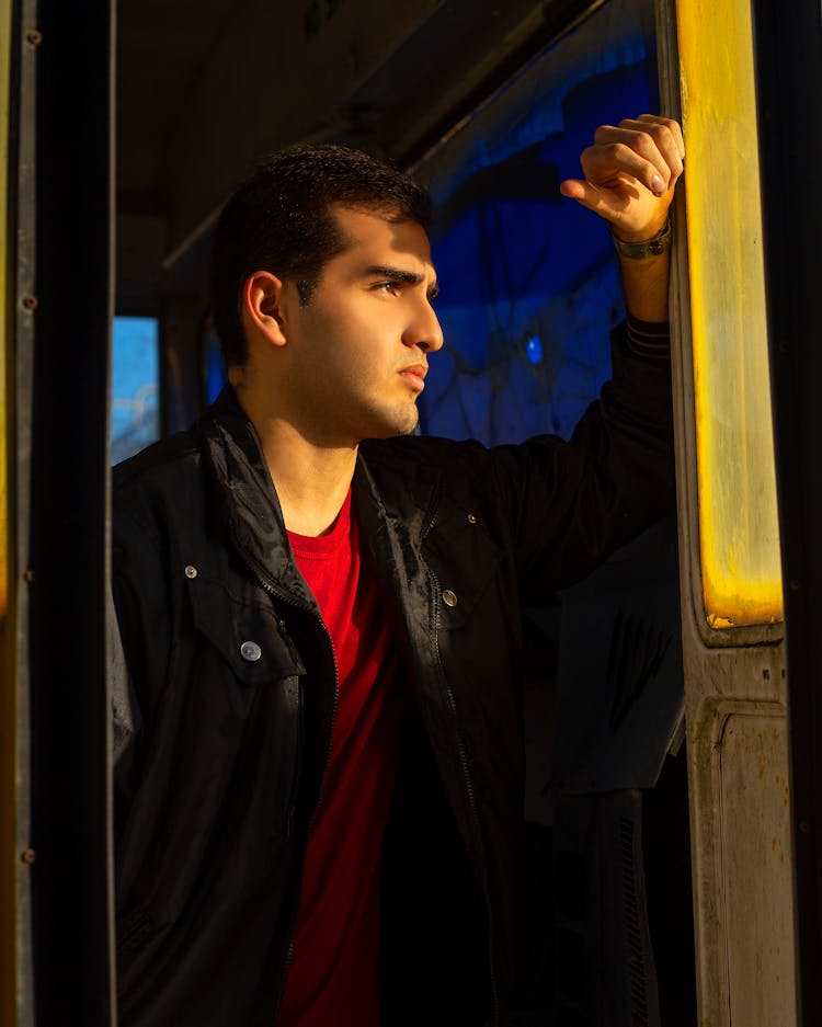 Thoughtful Man Standing In Bus Doorway In Sunlight