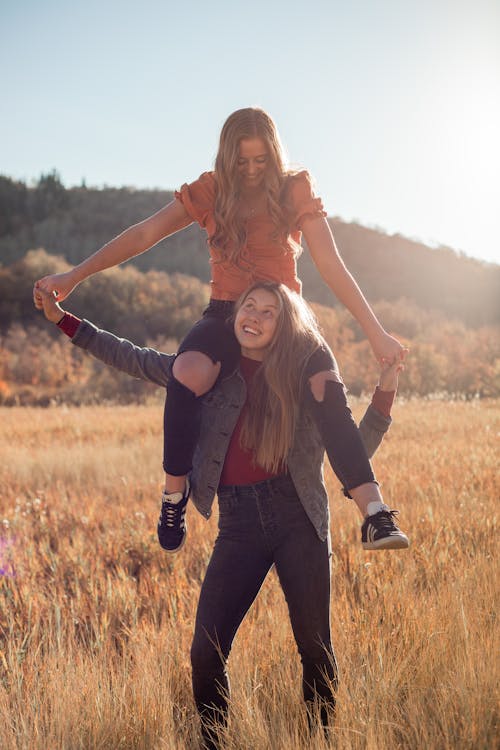 Happy woman carrying best friend on shoulders in field