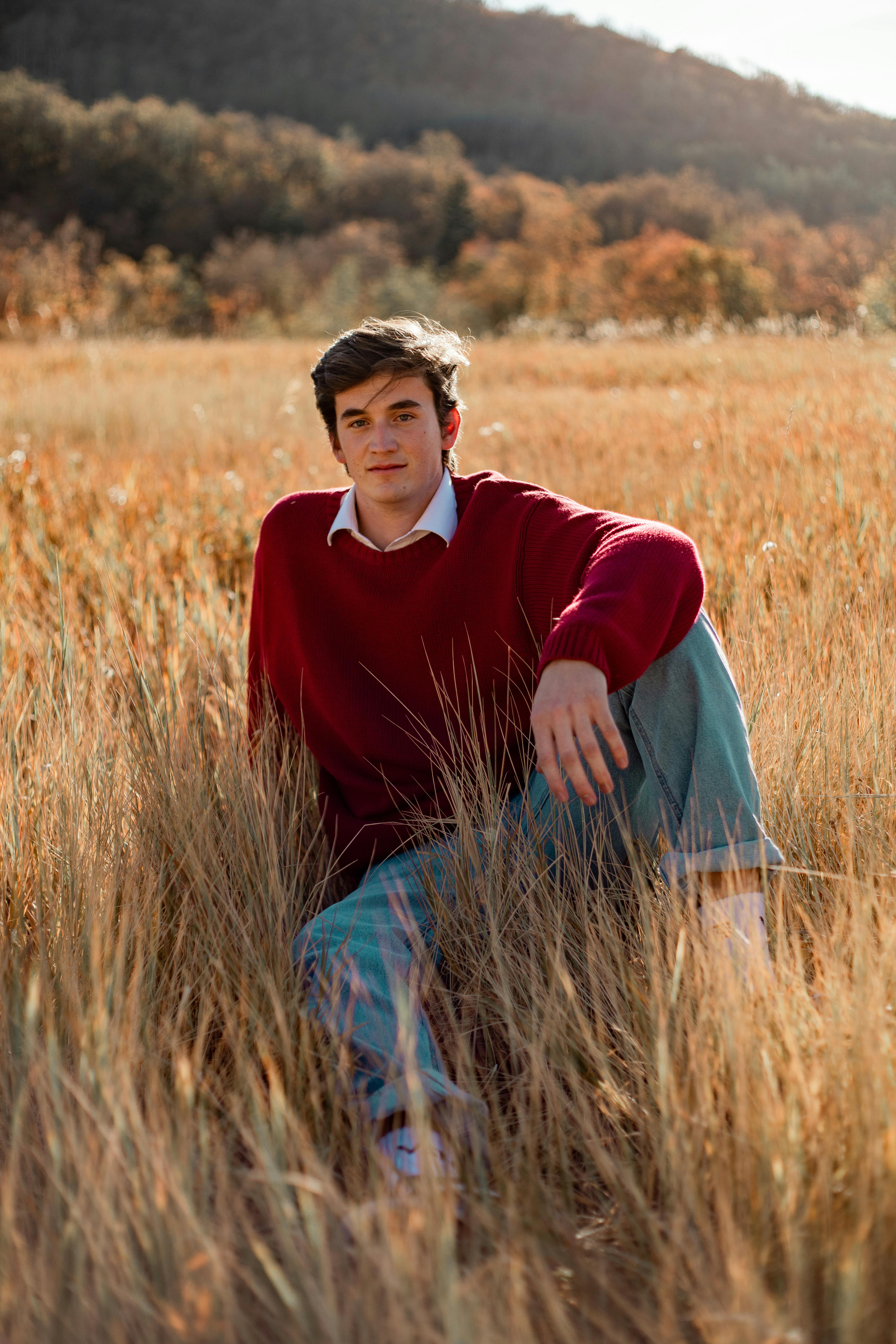 Portrait of a young man sitting in a field during fall. Vibrant colors and natural setting.