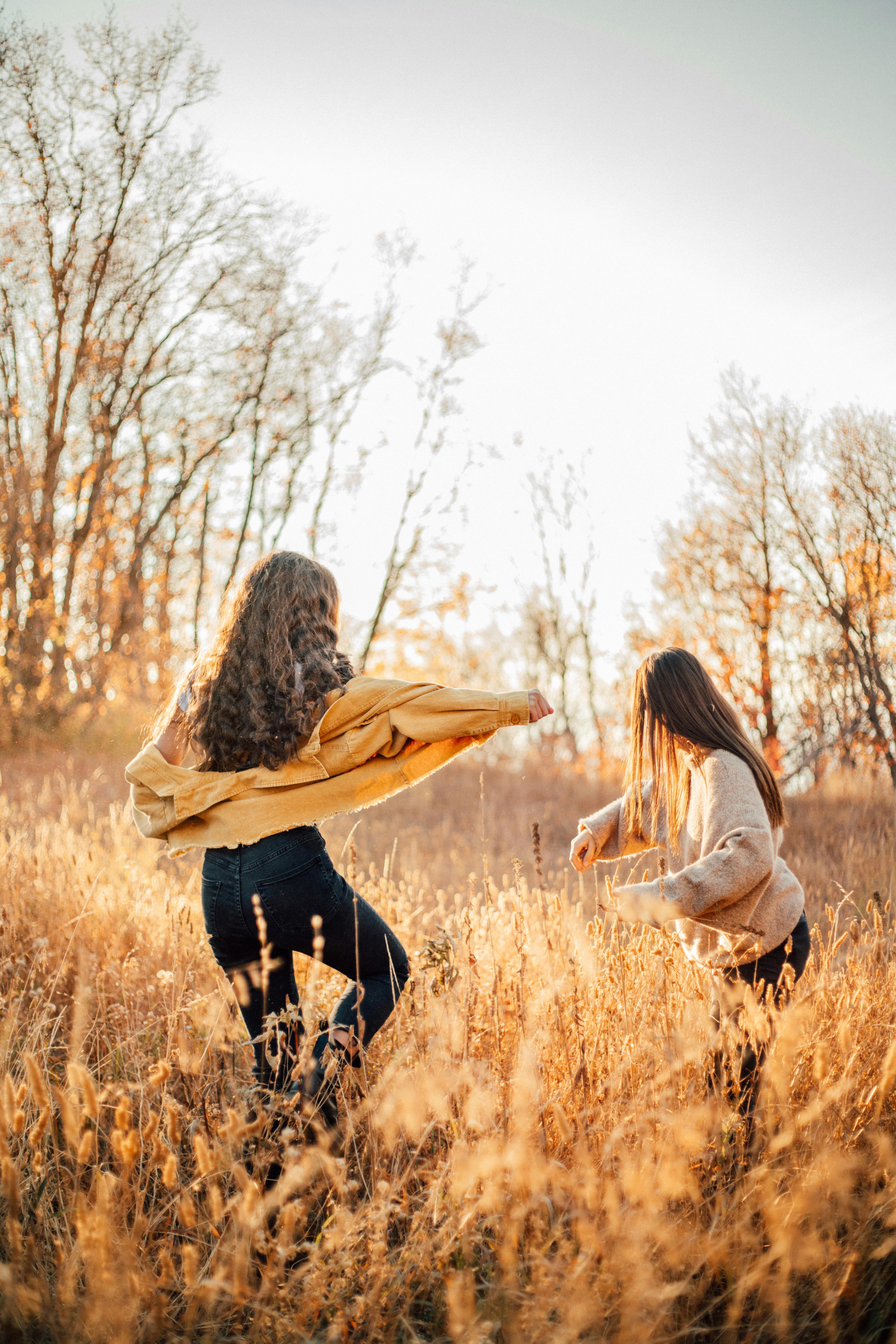 backview of carefree young women on a brown grass field