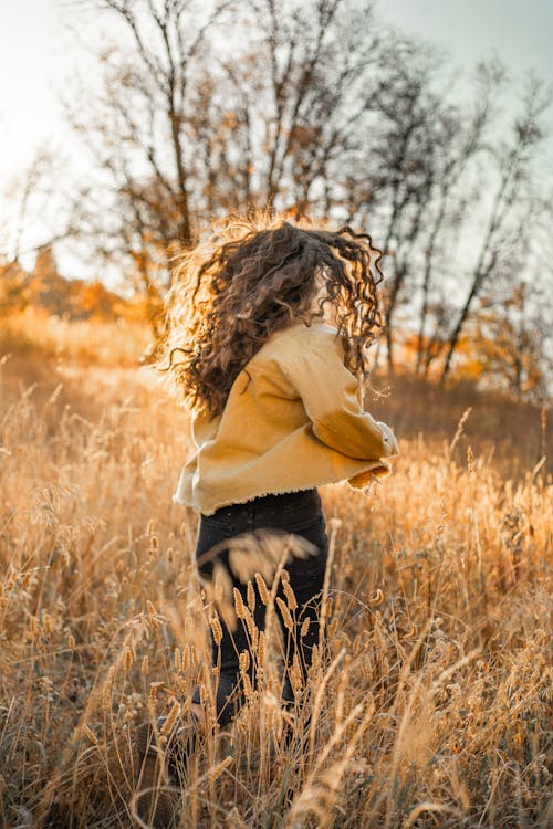 Woman in Yellow Long Sleeve Shirt and Black Pants Standing on Brown Grass Field