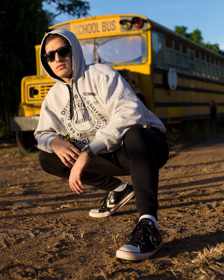 Guy Sitting Near School Bus On Ground In Countryside