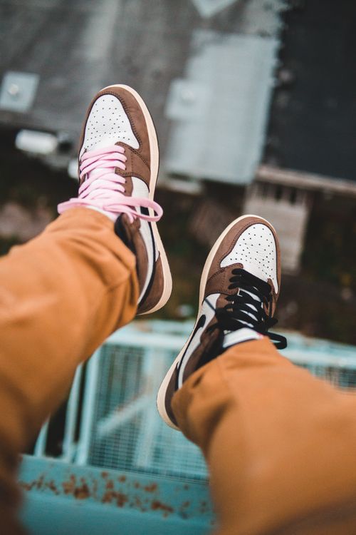 Free From above crop legs of anonymous man in jeans and sneakers sitting on high stairway above street Stock Photo