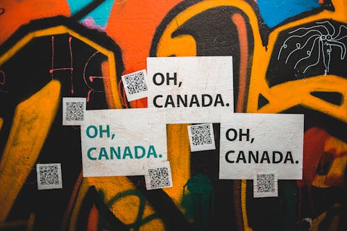 Colorful graffiti wall with Oh Canada inscription and QR codes on city street