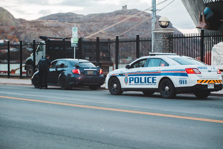 Policeman Standing Near Modern Car On Road