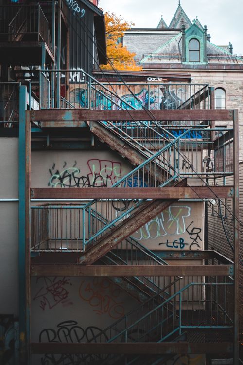 Free Graffiti on wall of aged building with shabby rusty fire escape in daytime Stock Photo