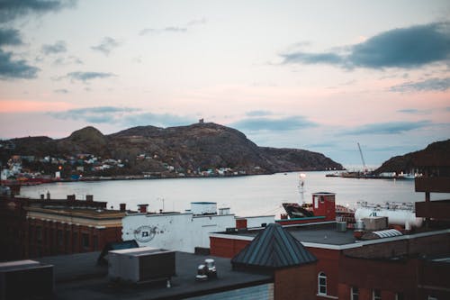 Picturesque scenery of sea port located in coastal town in hilly terrain against cloudy sunset sky