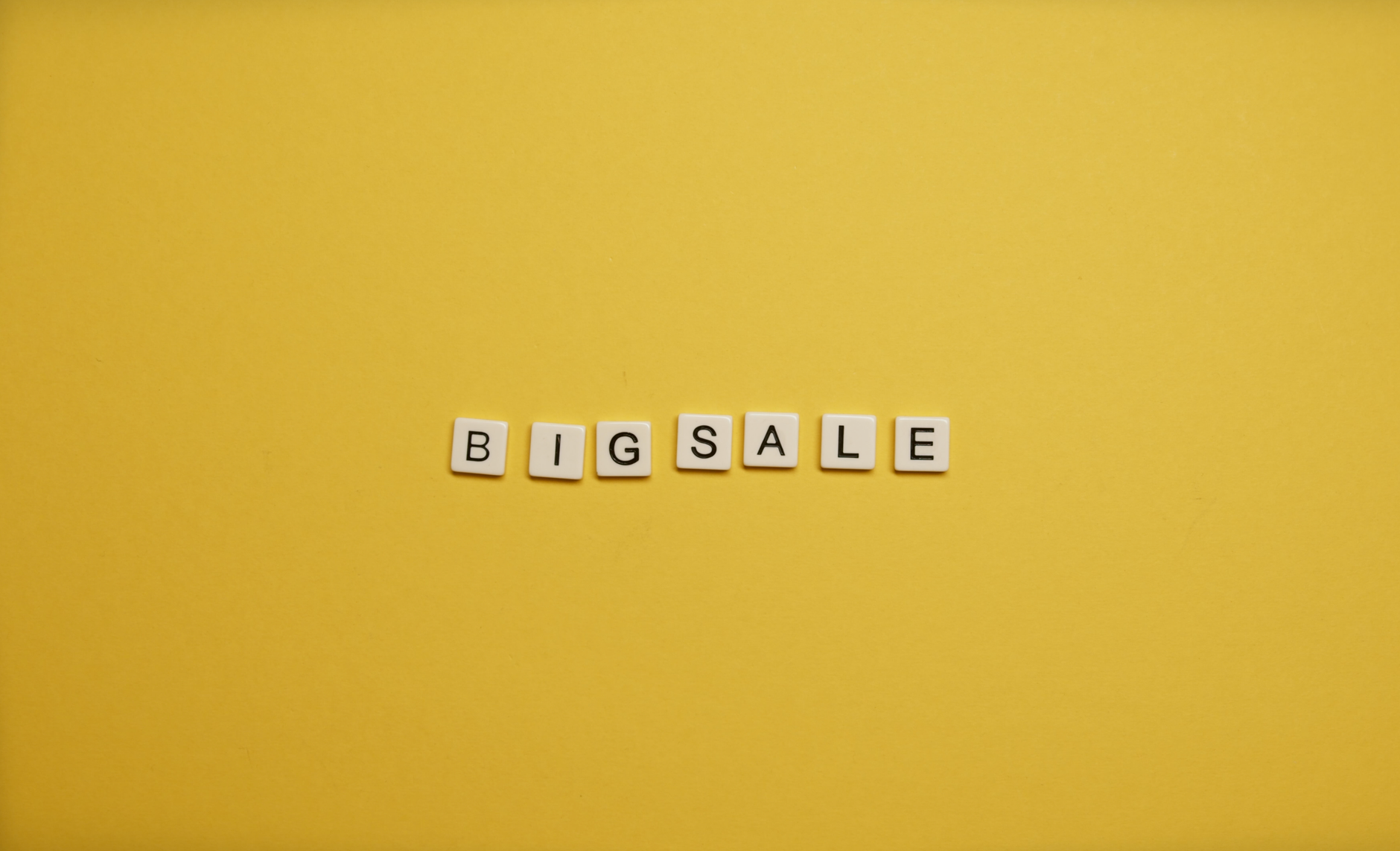 Alphabet tiles spelling 'BIG SALE' on a bright yellow backdrop.