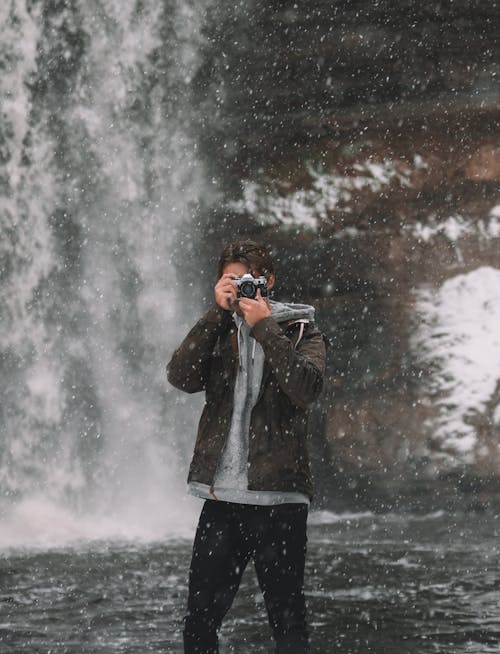 Man taking photo at waterfall in winter