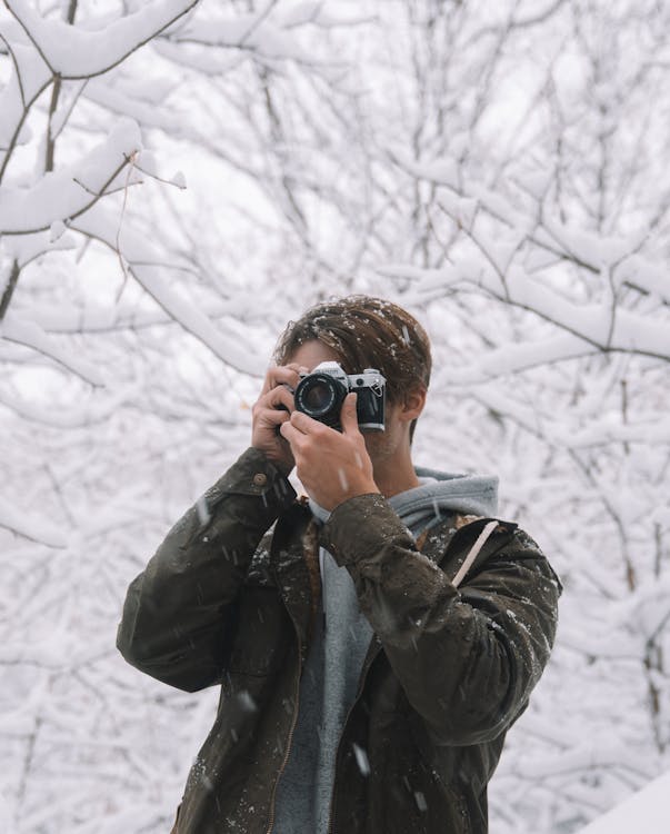Male photographer taking photo in winter woods