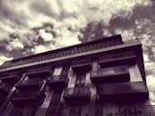 低角度视角下的现代建筑，玻璃阳台映衬着多云的天空