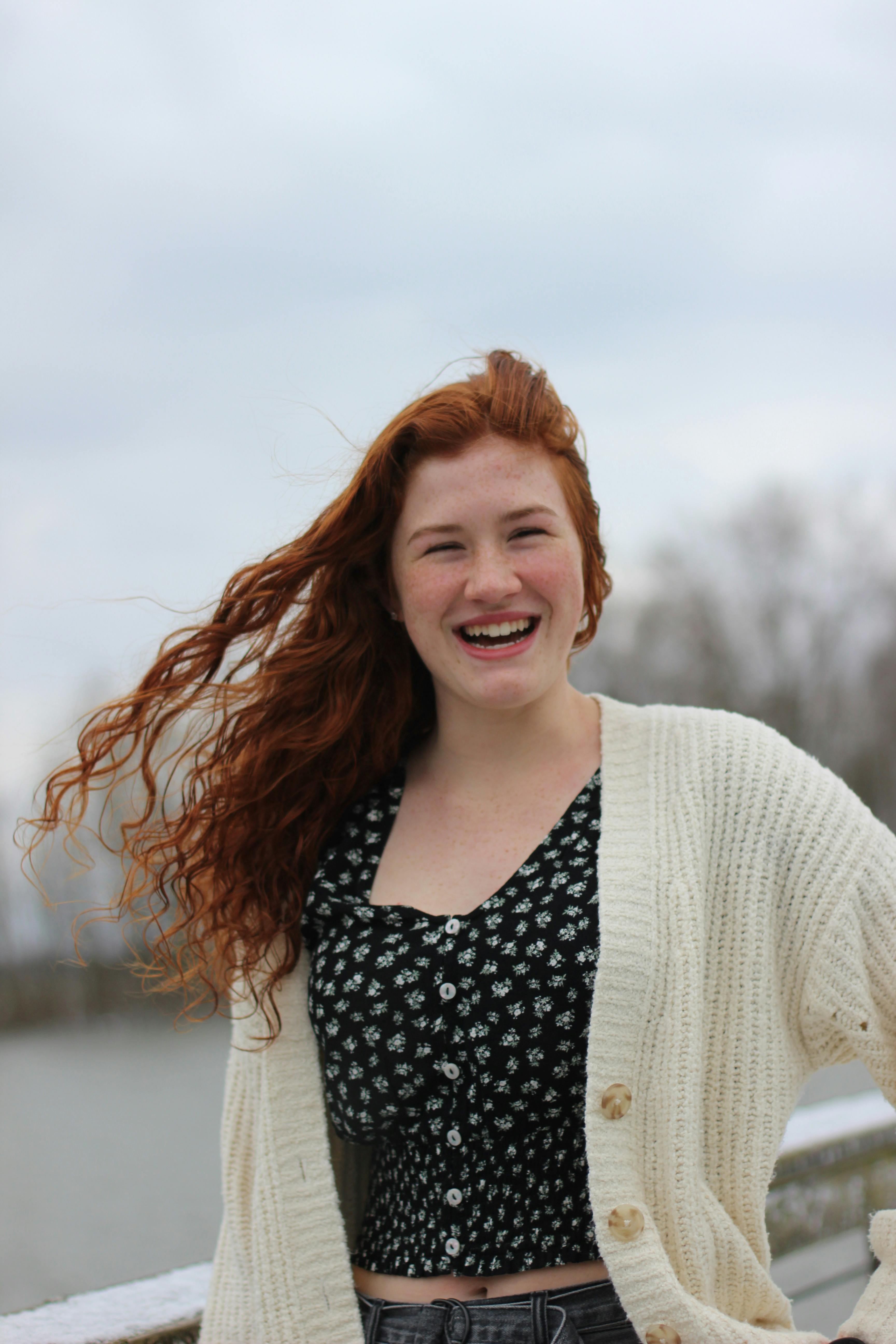 Happy red-haired woman smiling and enjoying a breezy outdoor day.