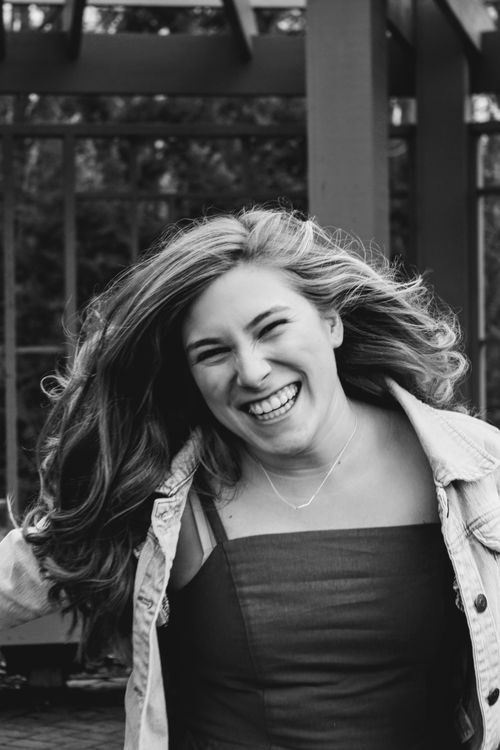 Free Black and white portrait of a joyful woman laughing outdoors captured with expressive emotion. Stock Photo