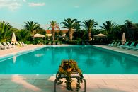 Relax by a serene poolside surrounded by lush palm trees in Italy, capturing summer bliss.