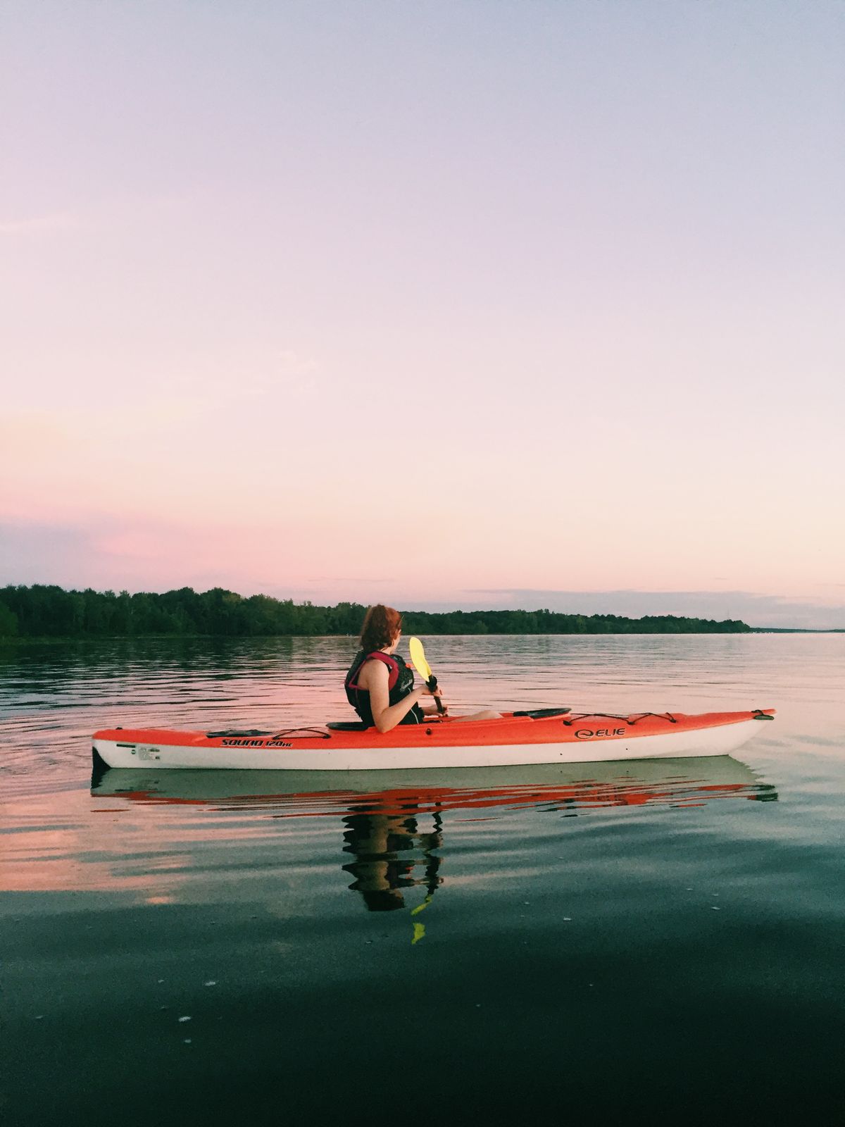 Kayaker on a tranquil lake at sunset