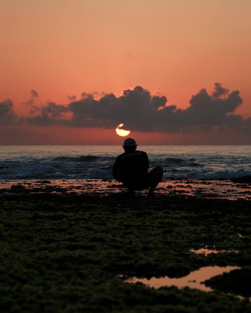 Silhouette of Man Sitting Near Seashore