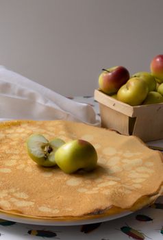 A delicious pancake served with fresh green apples on a table, showcasing a perfect breakfast scene.