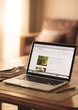 A cozy indoor workspace featuring an open laptop on a wooden table with soft lighting.