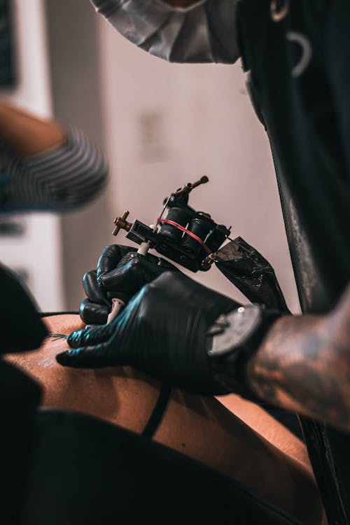 A Tattoo Artist Tattooing a Client
