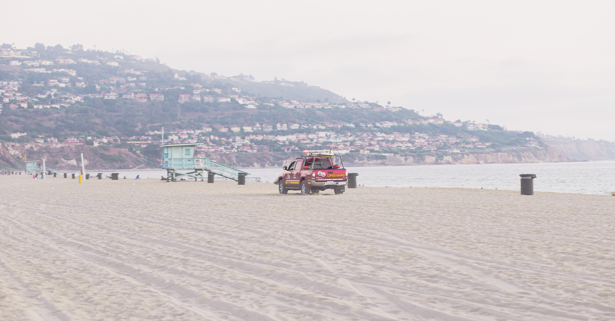 A sunny day at Redondo Beach with a lifeguard tower and pickup truck on the sand.