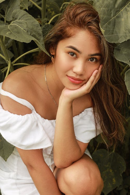 Pretty Asian woman leaning on hand in garden