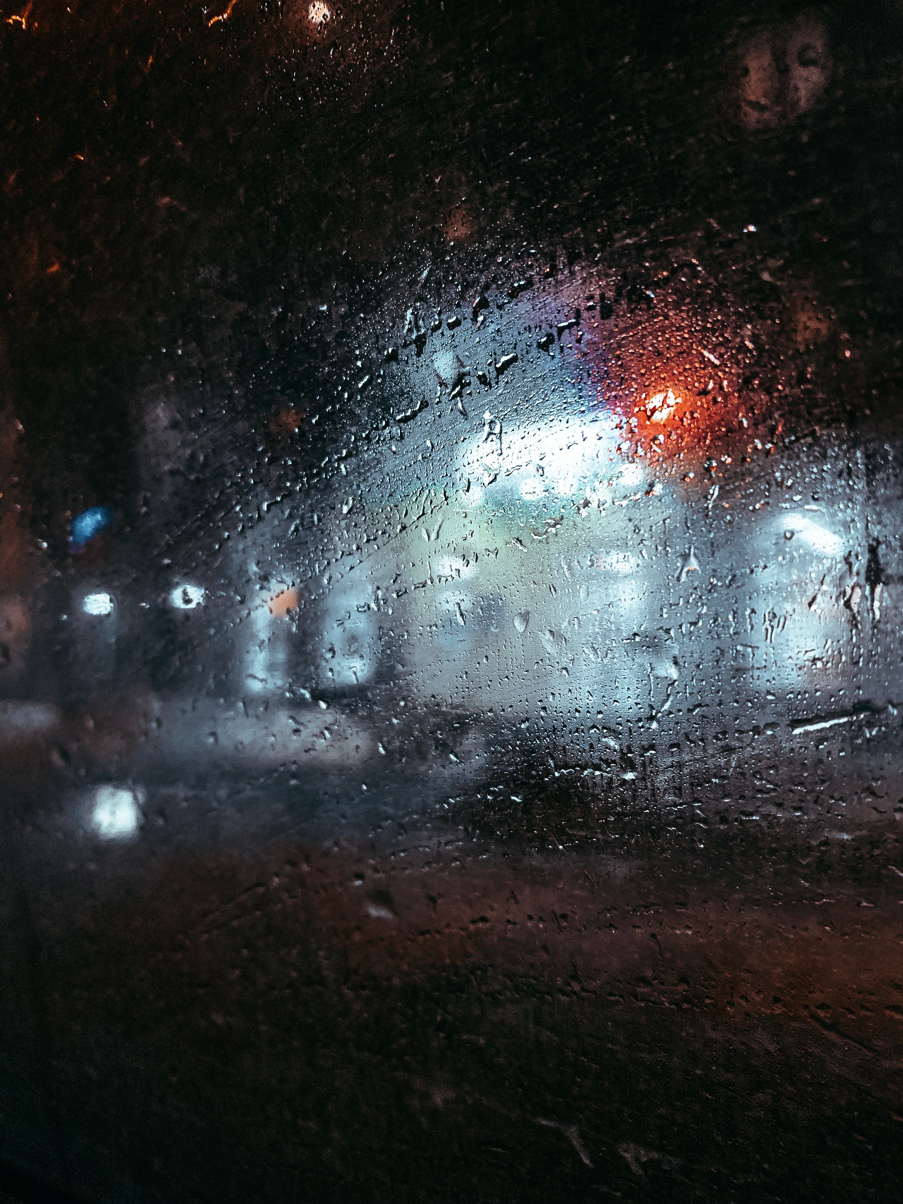 城市夜景寒冷，雨滴打在窗户上，营造出反光的艺术氛围