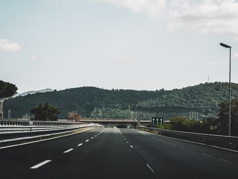 Peaceful highway cutting through lush Italian hills under a clear sky.