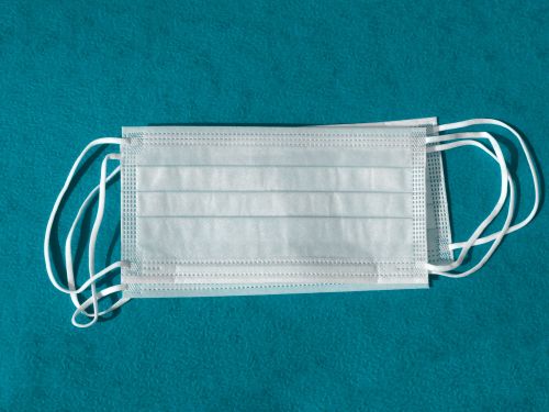 Free A surgical face mask displayed against a blue background, highlighting pandemic safety measures. Stock Photo