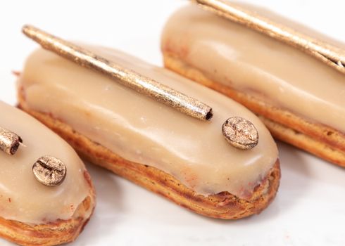 From above of delicious eclairs topped with coffee glaze and golden coffee beans