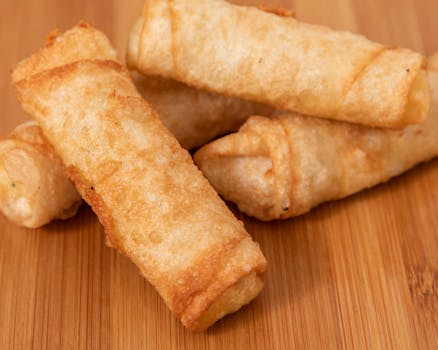 Close-up of crispy golden spring rolls served on a wooden board, perfect for appetizers or snacks.