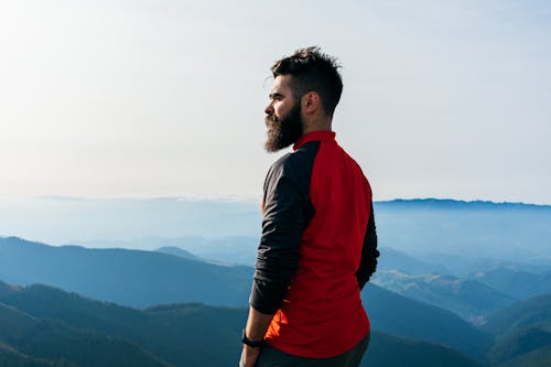 Man in Red and Black Long Sleeves standing on Top of Mountain