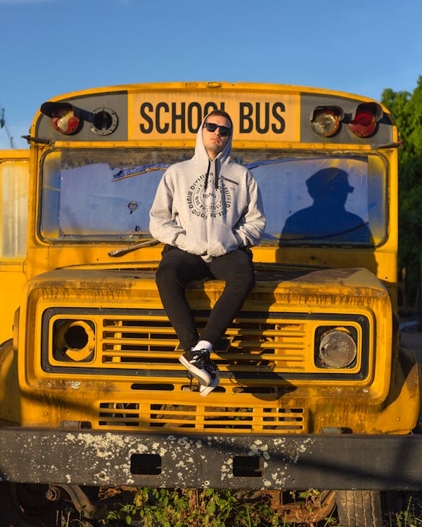 Man Sitting on a Hood of a School Bus