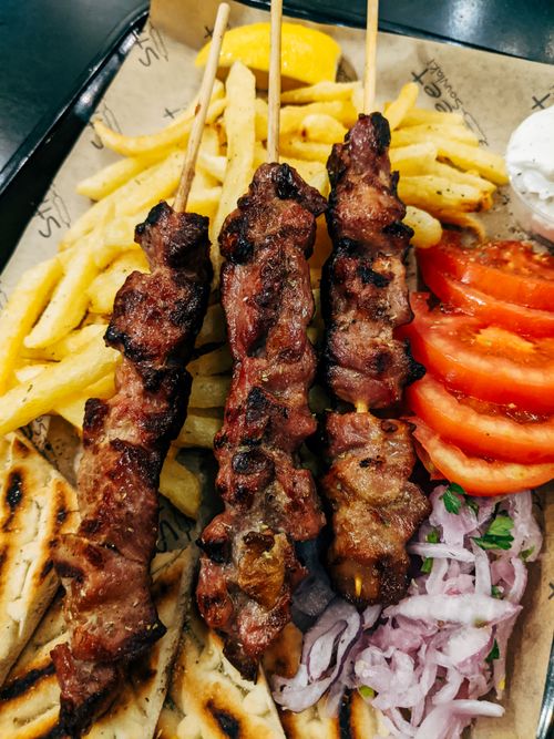 Free Tasty grilled skewers served with fries, veggies, and pita bread for a savory meal. Stock Photo