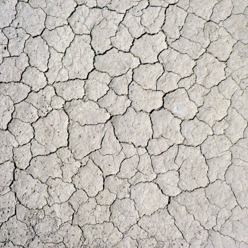 From above textured background of drought cracked dry soil of wild land in dessert terrain in nature in daylight outside