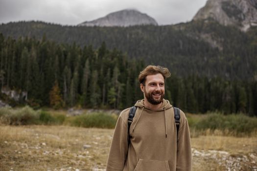 一名留着胡须的男子在森林覆盖的山区徒步旅行时微笑着