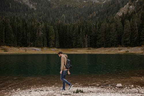 Man in Brown Hoodie walking on Lakeside