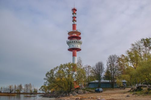 Free A tall telecommunications tower by a lakeside with autumn foliage surrounding it. Stock Photo
