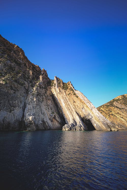 High ridge against sea under blue sky