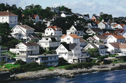 White residential houses located on hill in small town on shore of blue rippling sea