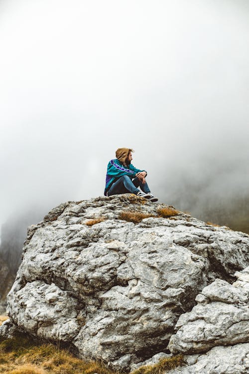 A Man Wearing Jacket Sitting on the Rock