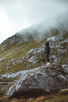 云雾缭绕的山间岩石上，一个人正拥抱孤独与冒险