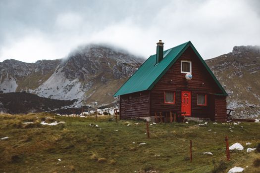 云雾缭绕的山地间，一座迷人的木制小屋坐落在高耸的山峰旁