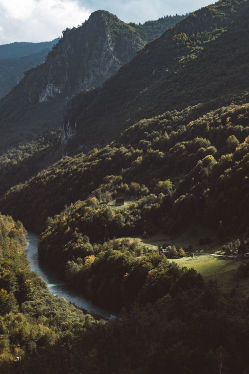 Free A breathtaking aerial shot of a serene mountain valley with a winding river and lush greenery. Stock Photo