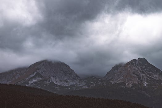Moody mountain scene with cloudy sky and rugged peaks creating a dramatic setting.