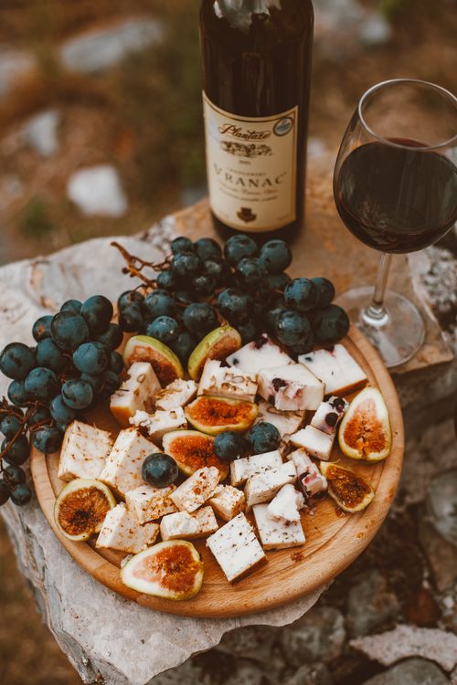 Free An elegant setting of wine, cheese, and grapes on a wooden platter outdoors. Stock Photo