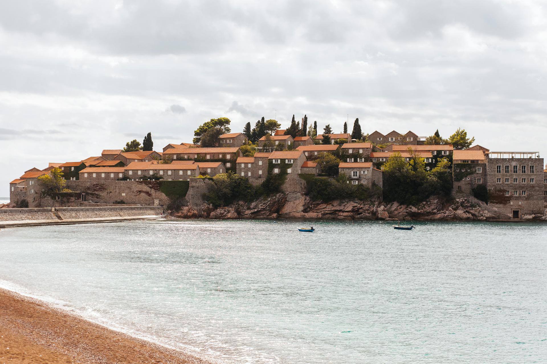Idyllic coastal view of Sveti Stefan, a picturesque island resort in Montenegro with charming orange-roofed buildings.