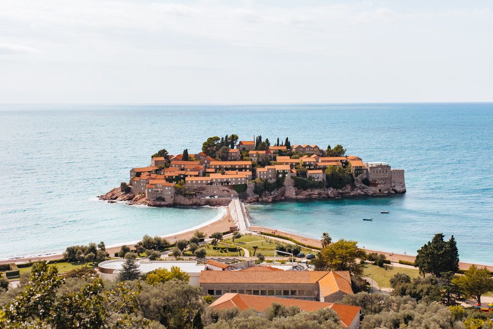 Vederea clasică de la belvedere asupra insulei Sveti Stefan, cu istmul și plajele simetrice