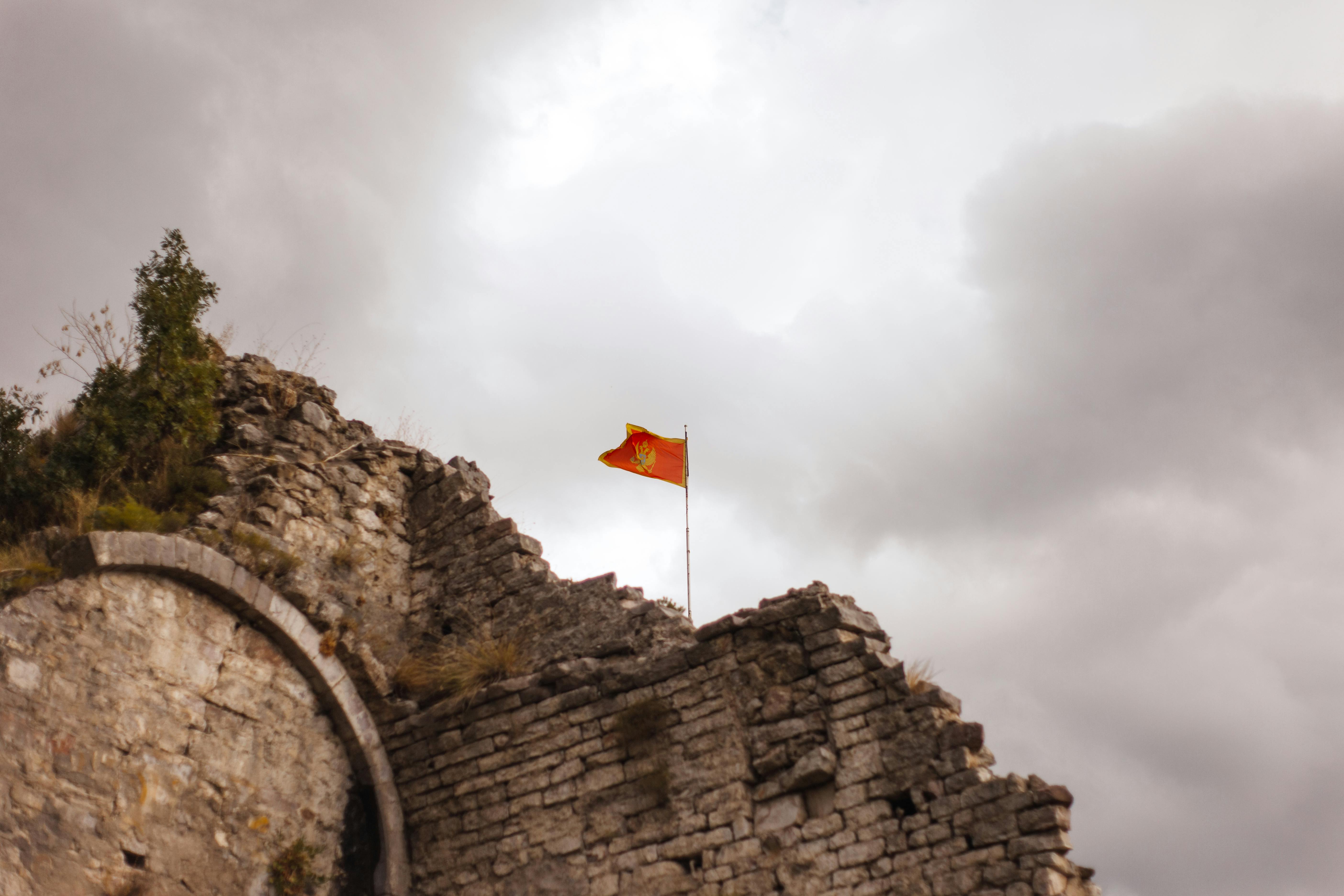 low angle shot of waving flag on a ruined brick wall